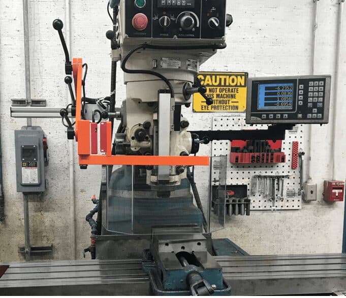 Vintage Bridgeport-style milling machine with orange swing-arm chip shield