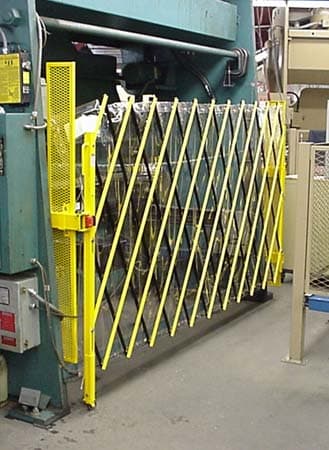 Yellow expandable scissor gate mounted on a press brake